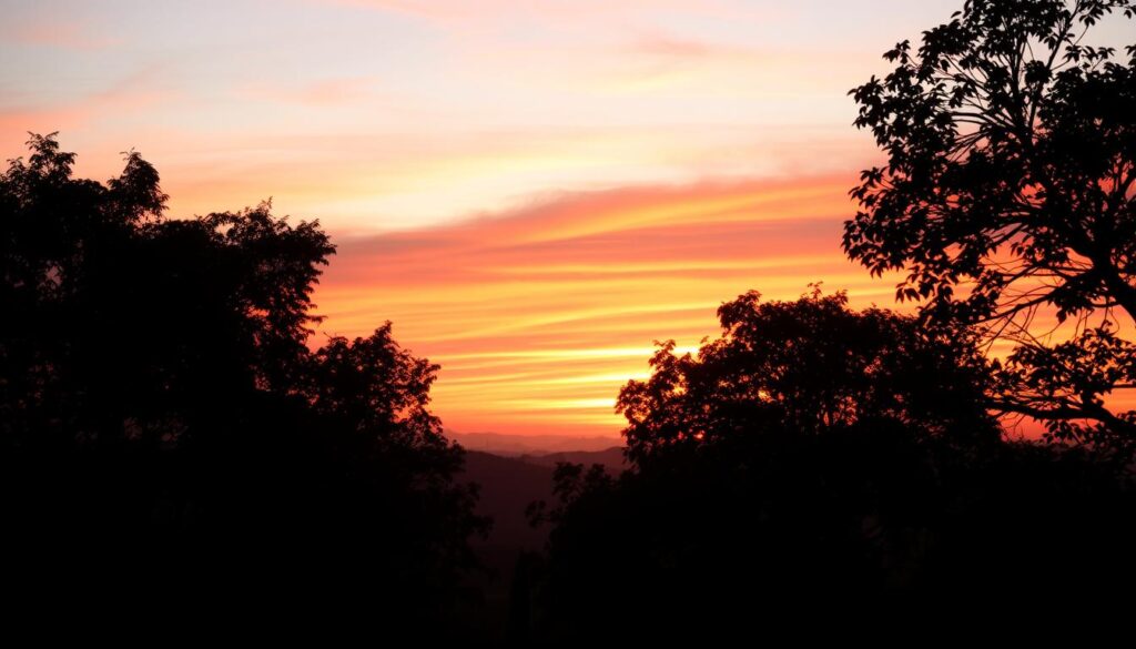 A breathtaking scene depicting the phenomenon of sunlight scattering in the atmosphere, particularly focusing on the vibrant hues of a red sky over Pandeglang. In the foreground, a silhouette of trees gently swaying, reflecting the late afternoon light. The middle ground shows a soft blend of oranges, pinks, and reds in the sky, illustrating the scattering of sunlight through atmospheric particles. In the background, distant hills fade gently into the horizon, providing a serene contrast to the vivid sky. The image is illuminated by a warm, golden hour glow, creating an ethereal and calm atmosphere. Capture the incredible beauty and scientific wonder of the red sky while emphasizing the natural elements present. Ensure meticulous details in lighting and color to convey the mood effectively.